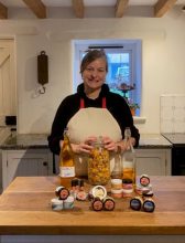 Customer Cornish Calendula Smiling woman behind a desk displaying a range of cosmetic products