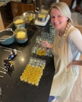 Customer Gems Skincare Woman working at a bench with lots of jars containing yellow product