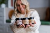 Customer BareskinWellness A woman in blurred background holding out 3 jars of cosmetic product to the camera in the foreground