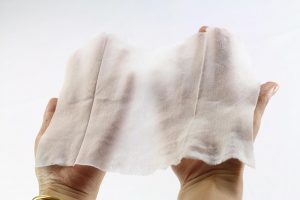 A wet wipe being held by 2 hands